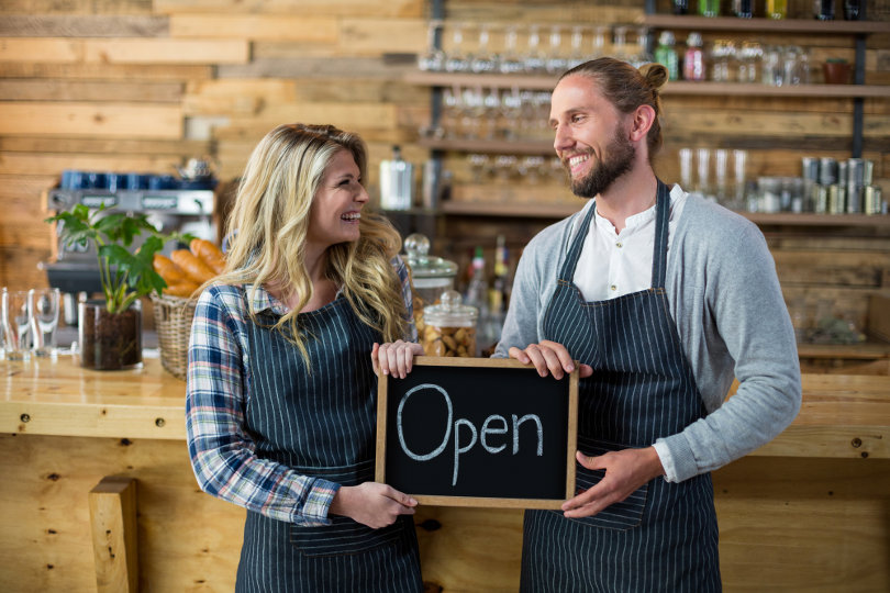 Restaurant owners holding open sign