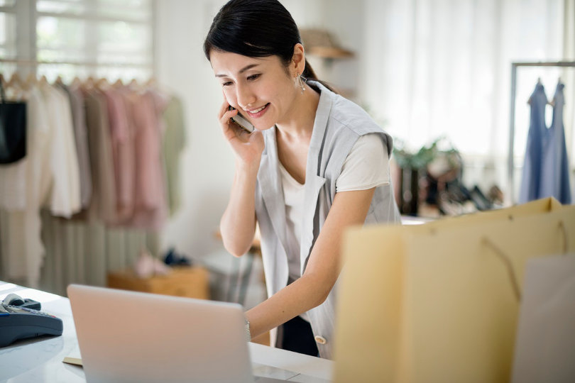 Dueño de una tienda de moda modesta hablando con un cliente