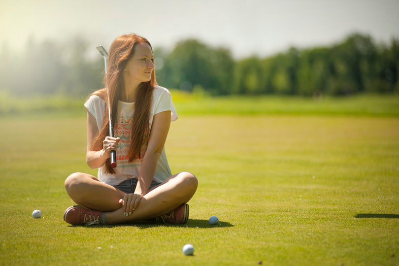 Female golfer sitting on the fairway