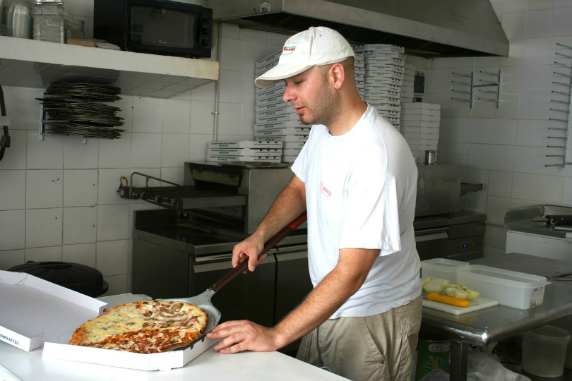 Husband placing pizza in box in couple's business