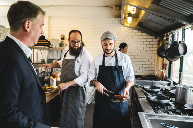 Kitchen manager talking with the chef and kitchen hand