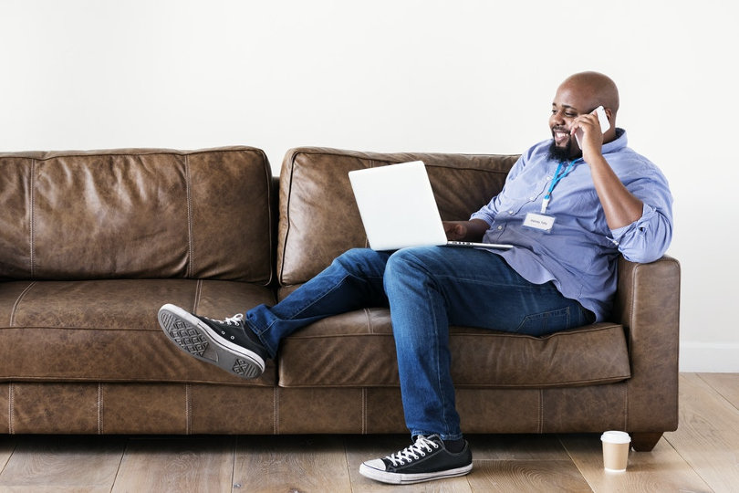 Hybride Belegschaft, die mit einem Laptop auf der Couch arbeitet